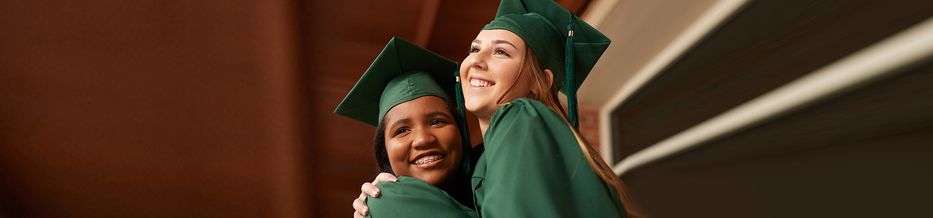  Two smiling Girl Scouts in green graduation caps and gowns 